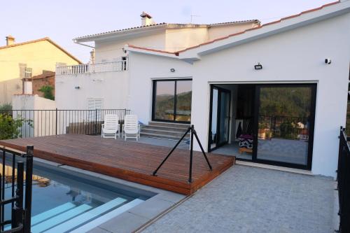a house with a wooden deck and a swimming pool at Casa Rio, Amalia in Ferreira do Zêzere