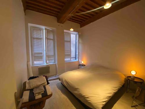 une chambre avec un grand lit et deux fenêtres dans l'établissement Old town - Vieux Lyon -50 m2 flat, à Lyon
