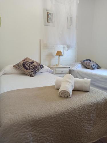 a room with two beds with a towel on a table at Villa Cuatro Encinas, Iznájar in Iznájar