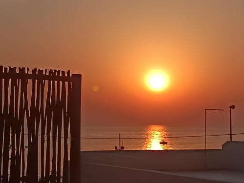 a sunset over a beach with a fence and the ocean at Riviera la lanterna in Scoglitti