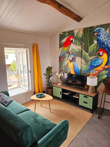a living room with a large painting of parrots on the wall at Gite "RIO", parking securise in La Roche-sur-Yon