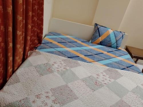 ein Bett mit einer Decke und Kissen darauf in der Unterkunft All in One in Schardscha