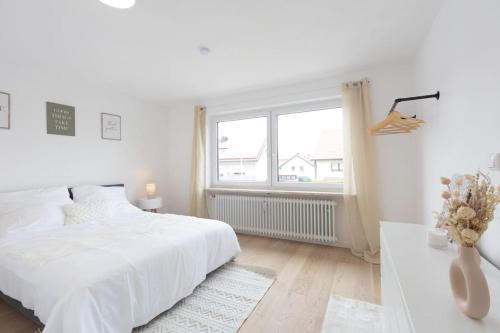Stylish Apartment near Munich في مورنويس: غرفة نوم بيضاء مع سرير أبيض ونافذة