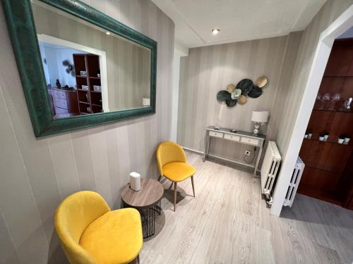 a living room with two yellow chairs and a mirror at Apartamenticos La Paz I in Zaragoza