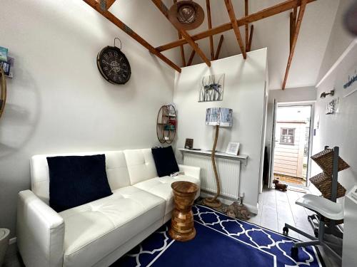 Nautical South Self-contained Dog Friendly Annexe في فيرهام: غرفة معيشة مع أريكة بيضاء وساعة على الحائط