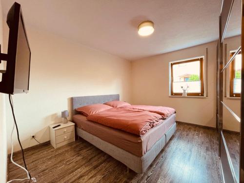 a bedroom with a bed and a flat screen tv at Ferienwohnung Etzelbach in Etzelbach