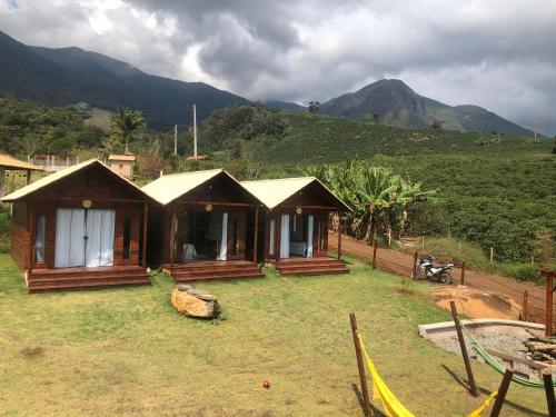 a small house in a field with mountains in the background at Recanto dos Pássaros in Alto Caparao