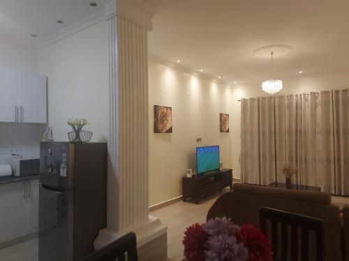 a living room with a couch and a television at Beautiful 2-Bed Apartment in Akright City Bwebajja in Namulanda