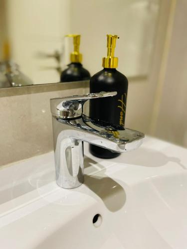 a bathroom sink with a faucet and a bottle of alcohol at Insta-worthy staycation at 2BR luxury Apt - Podomoro Empire Tower in Medan