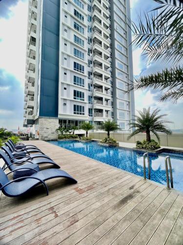 a row of chaise lounge chairs on a wooden deck in front of a building at Insta-worthy staycation at 2BR luxury Apt - Podomoro Empire Tower in Medan