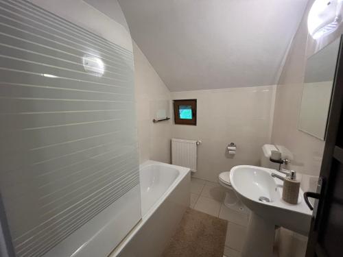 ein weißes Badezimmer mit Badewanne und Waschbecken in der Unterkunft Trout Cottage in Bran