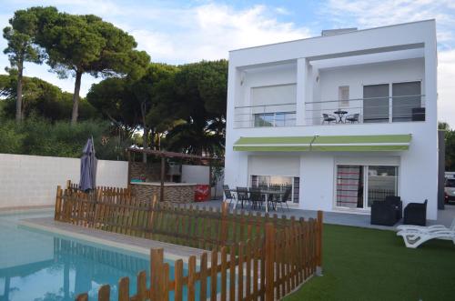 een wit huis met een zwembad en een hek bij Villa Cristal in Chiclana de la Frontera