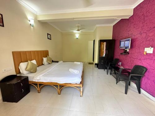 a bedroom with a bed and a pink wall at Hotel Leela Inn Candolim in Marmagao