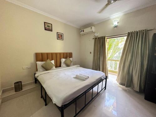 a bedroom with a bed and a large window at Hotel Leela Inn Candolim in Marmagao