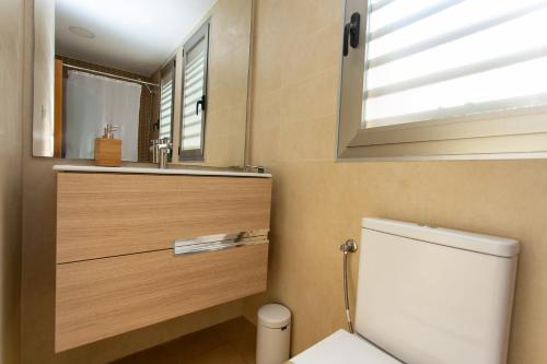 a bathroom with a toilet and a sink and a mirror at 4-Seasons Penthouse Cullera in Cullera