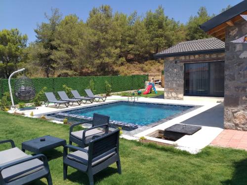 een zwembad in een tuin met stoelen eromheen bij Fethiye Havuzlu Villa in Fethiye