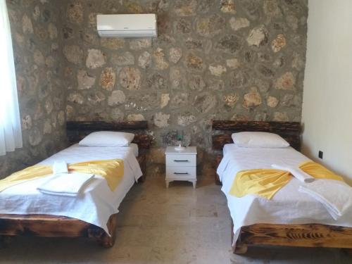 twee bedden in een kamer met een stenen muur bij Fethiye Havuzlu Villa in Fethiye