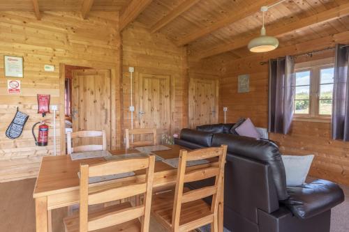 a living room with a table and a leather couch at Pastures Green Cabin (Oak Tree Lane) in Okehampton