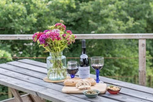 a table with a bottle of wine and a vase of flowers at Pastures Green Cabin (Oak Tree Lane) in Okehampton