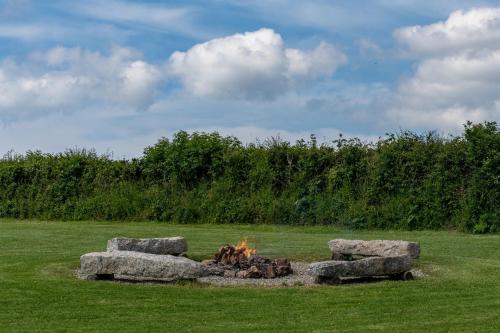 a fire pit in a field with large rocks at Pastures Green Cabin (Oak Tree Lane) in Okehampton