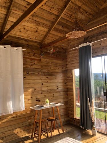 Habitación de madera con mesa y ventana en Recanto dos Pássaros en Caparaó Velho