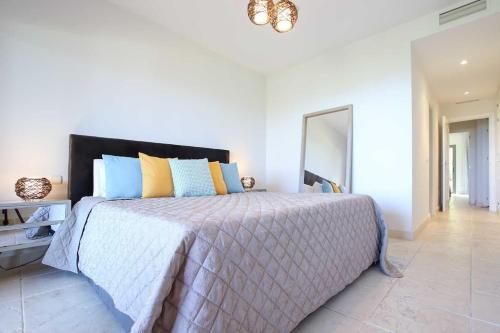 a bedroom with a large bed with blue and yellow pillows at Apartamento en residencial de lujo Los Flamengos in Estepona