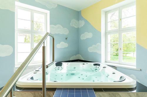 Gutshaus Groß Helle في Mölln: حوض استحمام في غرفة مع سحب مرسومة على الحائط