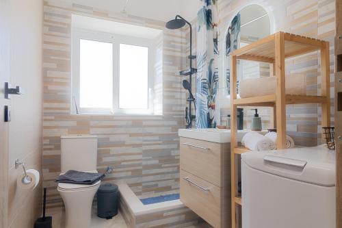 baño con lavabo y aseo y ventana en Vivid Stays Petralona, en Atenas