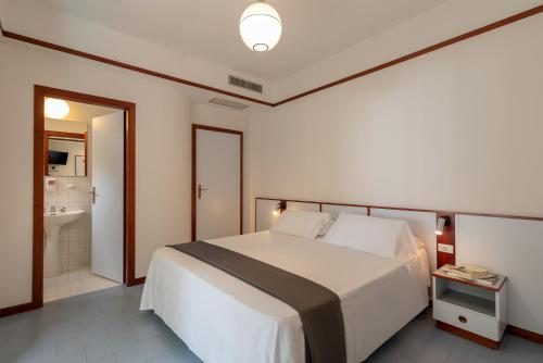 a bedroom with a large white bed and a bathroom at Hotel Baltic in Giulianova