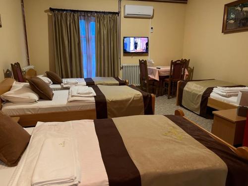 una camera d'albergo con quattro letti e una televisione di Hotel Dva Goluba a Pale