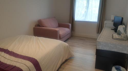 1 dormitorio con 1 cama, 1 silla y TV en Apsley home, Hemel Hempstead, en Hemel Hempstead