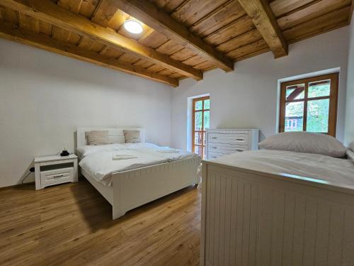 een slaapkamer met 2 bedden en een houten plafond bij Apartmány Jezerné in Velké Karlovice