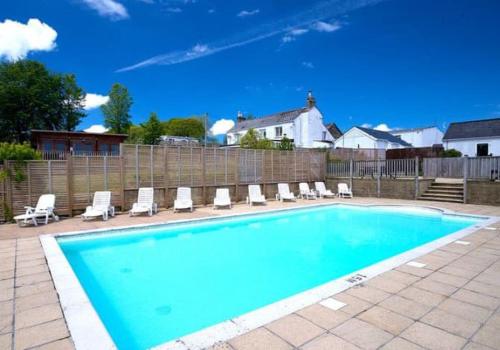 a swimming pool with lounge chairs and a fence at Roecliff in St Austell