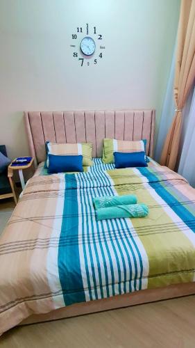a bedroom with a large bed with a clock on the wall at La Suite@Alanis Residence in Sepang