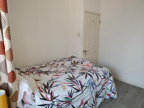 a bedroom with a bed with a floral comforter at Wulfstan House Quiet, Neat, Comfy - 2 min to Central line, Westfield, Notting hill in London