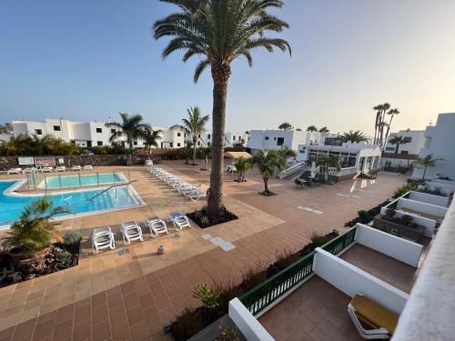uma vista aérea de um resort com uma piscina e palmeiras em Apartamentos Acuario Sol em Puerto del Carmen