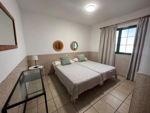 1 dormitorio con cama y mesa de cristal en Apartamentos Acuario Sol en Puerto del Carmen