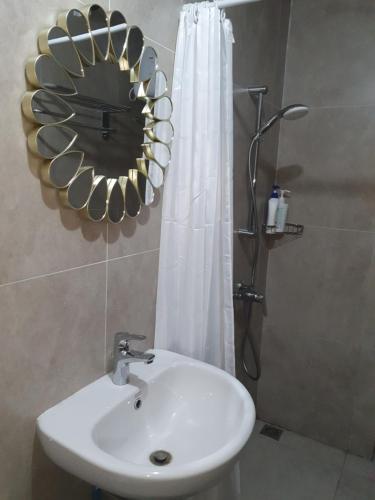 uma casa de banho com um lavatório, um espelho e um chuveiro em Lenggo - Apartement Meisterstadt Pollux Habibie 52-05 em Kangboi