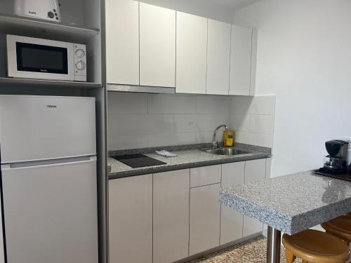 a white kitchen with a refrigerator and a sink at Apartamentos Acuario Sol in Puerto del Carmen
