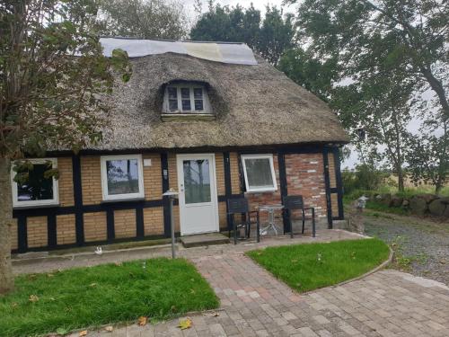 a small house with a thatched roof at Cozy Hideaway - Rustic Charm & Outdoor Adventure 1 in Hornsyld