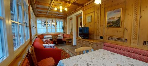 a room with a table and chairs and a television at Garnì Stella Alpina in Canazei