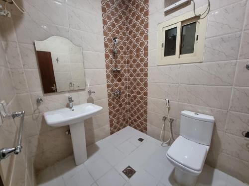 a bathroom with a white toilet and a sink at الديار الفاخرة للشقق المخدومة in Al Qunfudhah