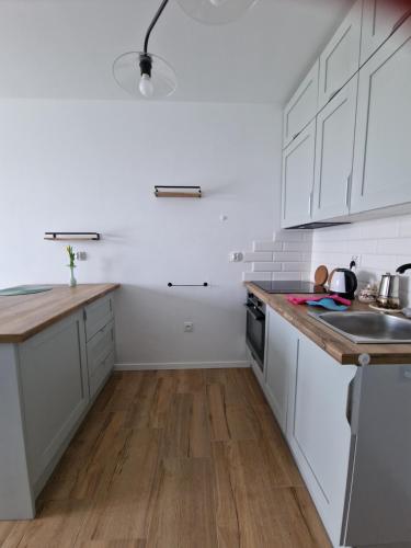 a kitchen with white cabinets and a wooden floor at Oława Chabrów in Oława