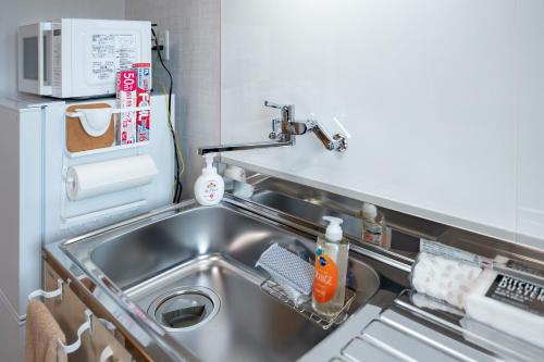 uma cozinha com um lavatório e um micro-ondas em 佐賀インターナショナルゲストハウスHAGAKURE 2号店 em Saga