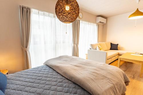 a bedroom with a bed and a couch and a window at 佐賀インターナショナルゲストハウスHAGAKURE 2号店 in Saga