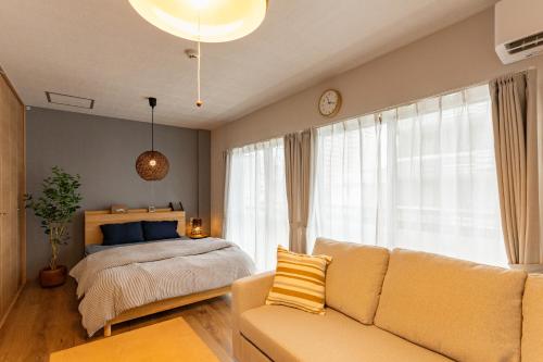 uma sala de estar com uma cama e um sofá em 佐賀インターナショナルゲストハウスHAGAKURE 2号店 em Saga