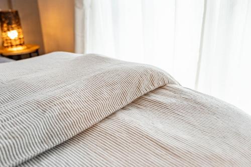 a bed with a striped blanket on top of it at 佐賀インターナショナルゲストハウスHAGAKURE 2号店 in Saga