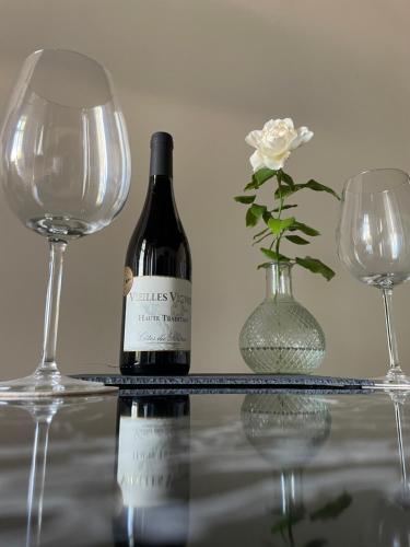 - une bouteille de vin et un vase avec une fleur dans l'établissement Appartement chic et de caractère !, à Saint-Cyr-au-Mont-dʼOr