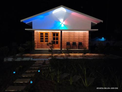 a house lit up at night with chairs in front at Merlys Fruit Garden - Resort at Thattekkad in Kotamangalam