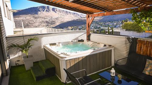 a hot tub on a balcony with a mountain in the background at Nofesh Arbel Suite with Jacuzzi near Sea of Galilee in Migdal